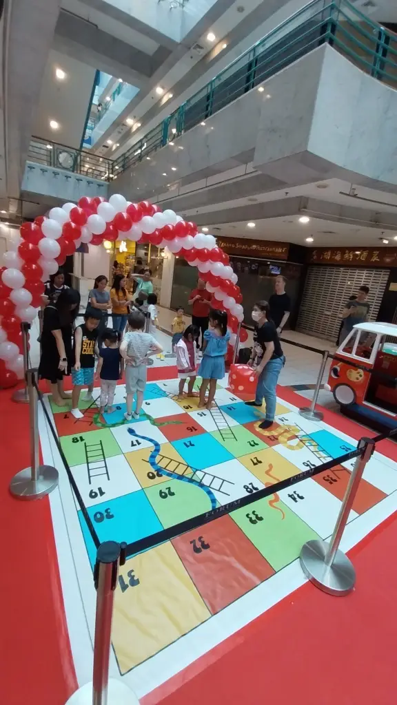 Red and white balloon arch with BIG snake and ladders game